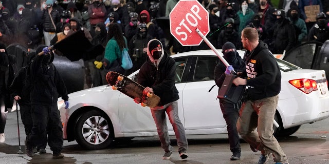 Protesters chase a street preacher, right, who was using a loudspeaker to deliver a sermon during a protest against police brutality, Sunday, Jan. 24, 2021, in downtown Tacoma, Wash. (Associated Press)