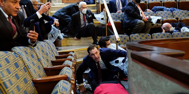 People shelter in the House gallery as protesters try to break into the House Chamber at the U.S. Capitol on Wednesday, Jan. 6, 2021, in Washington. (AP Photo/Andrew Harnik)