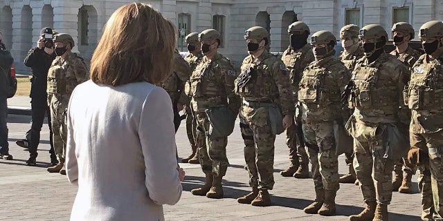 Nancy Pelosi addresses the National Guard troops in front of the Capitol.