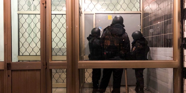 Police stand in front of a door of the apartment building where Oleg Navalny, brother of jailed opposition leader Alexei Navalny lives in Moscow, Russia, Wednesday, Jan. 27, 2021. Police are searching the Moscow apartment of jailed Russian opposition leader Alexei Navalny, another apartment where his wife is living and two offices of his anti-corruption organization. Navalny's aides reported the Wednesday raids on social media. (AP Photo/Mstyslav Chernov)