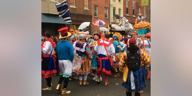 Costumed participants take to the streets of their south Philadelphia to celebrate the New Year of the Mummer tradition despite the annual event being officially canceled and large gatherings banned due to the coronavirus pandemic, Friday, January 1 2021 in Philadelphia.  (AP Photo / Ron Todt)