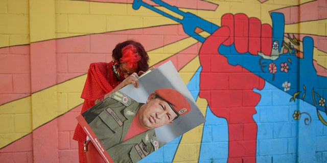 A government supporter known as "Caperucita," or Little Red Riding Hood, holds a photo of late Venezuelan President Hugo Chavez. (AP Photo/Matias Delacroix)