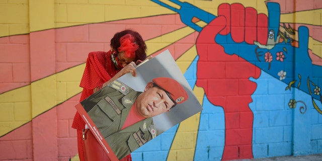 A government supporter known as "Caperucita," or Little Red Riding Hood, holds a photo of late Venezuelan President Hugo Chavez. (AP Photo/Matias Delacroix)