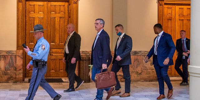 Lead by a Georgia State Trooper, Georgia Secretary of State Brad Raffensperger, center, exits the Georgia State Capitol building after hearing reports of threats, Jan. 6, in Atlanta.