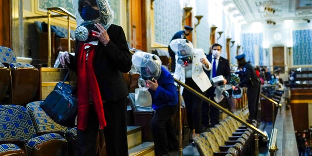 People shelter in the House gallery as protesters try to break into the House Chamber at the U.S. Capitol on Wednesday, Jan. 6, 2021, in Washington. (AP Photo/Andrew Harnik)