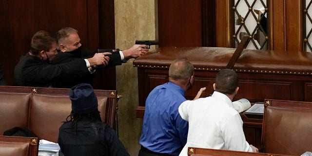 U.S. Capitol Police with guns drawn watch as protesters try to break into the House Chamber at the U.S. Capitol on Wednesday, Jan. 6, 2021, in Washington. (AP Photo/J. Scott Applewhite)