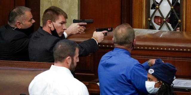 U.S. Capitol Police with guns drawn watch as protesters try to break into the House Chamber at the U.S. Capitol on Wednesday, Jan. 6, 2021, in Washington. (AP Photo/J. Scott Applewhite)