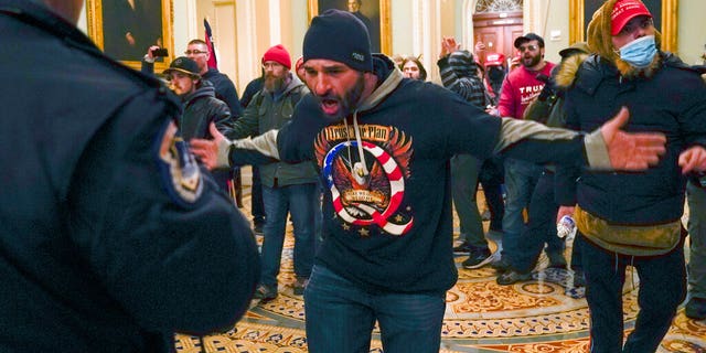 Trump supporters gesture to U.S. Capitol Police in the hallway outside of the Senate chamber at the Capitol in Washington, Wednesday, Jan. 6, 2021. (AP Photo/Manuel Balce Ceneta)