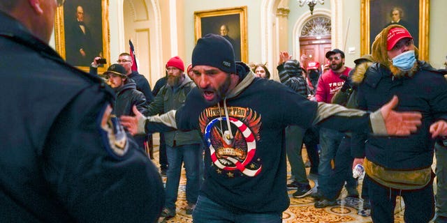 Trump supporters gesture to U.S. Capitol Police in the hallway outside of the Senate chamber at the Capitol in Washington, Wednesday, Jan. 6, 2021. (AP Photo/Manuel Balce Ceneta)