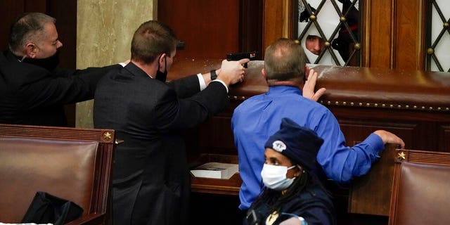Police with guns drawn watch as protesters try to break into the House Chamber at the U.S. Capitol on Wednesday, Jan. 6, 2021, a Washington. (Foto AP / J. Scott Applewhite)