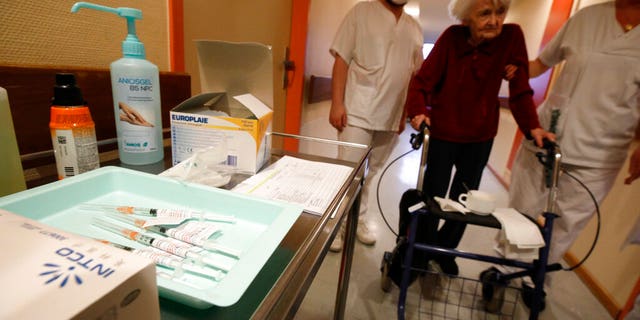 A resident is led to get the Pfizer-BioNTech COVID-19 vaccine at the Bois Fleuris nursing home in Strasbourg in eastern France, Jan. 6, 2021. (Associated Press)