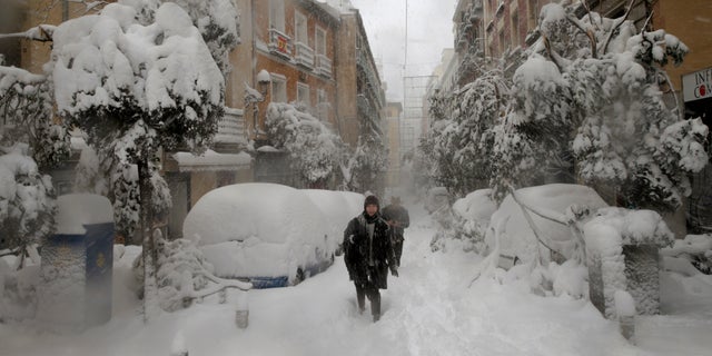 People walk during a heavy snowfall in Madrid, Spain, Saturday, Jan. 9, 2021. An unusual and persistent blizzard has blanketed large parts of Spain with snow, freezing traffic and leaving thousands trapped in cars or in train stations and airports that had suspended all services as the snow kept falling on Saturday. The capital, Madrid, and other parts of central Spain activated for the first time its red weather alert, its highest, and called in the military to rescue people from cars vehicles trapped in everything from small roads to the city's major thoroughfares. (AP Photo/Andrea Comas)