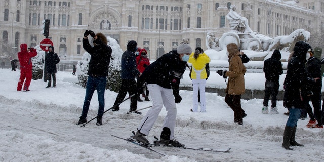 A woman skies past the Cibeles monument in front of the City Hall during a heavy snowfall in central Madrid, Spain, Saturday, Jan. 9, 2021. An unusual and persistent blizzard has blanketed large parts of Spain with snow, freezing traffic and leaving thousands trapped in cars or in train stations and airports that had suspended all services as the snow kept falling on Saturday. The capital, Madrid, and other parts of central Spain activated for the first time its red weather alert, its highest, and called in the military to rescue people from cars vehicles trapped in everything from small roads to the city's major thoroughfares. (AP Photo/Paul White)