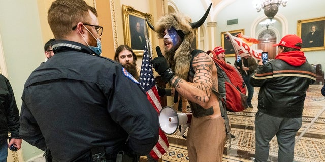 Supporters of President Trump are confronted by U.S. Capitol Police officers outside the Senate Chamber inside the Capitol in Washington. An Arizona man seen in photos and video of the mob wearing a fur hat with horns was also charged Saturday in Wednesday's chaos. Jacob Anthony Chansley, who also goes by the name Jake Angeli, was taken into custody Saturday, Jan. 9. (AP Photo/Manuel Balce Ceneta, File)