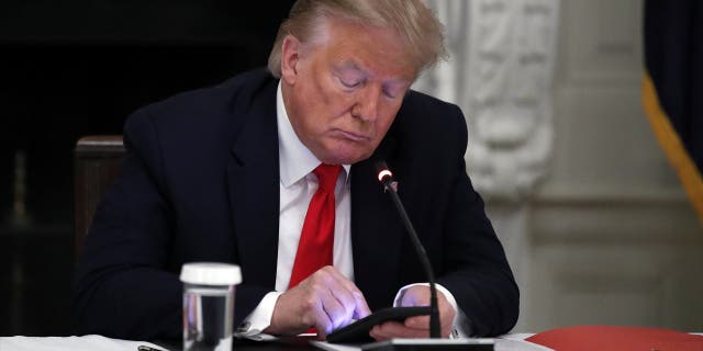 In this Thursday, June 18, 2020, file photo, President Donald Trump looks at his phone during a roundtable with governors on the reopening of America's small businesses in the State Dining Room of the White House in Washington. Trump this week could become the only president to ever be impeached twice. (AP Photo/Alex Brandon, File)