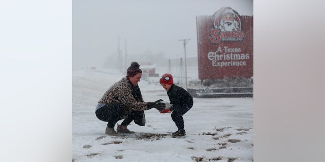 Heather makes a snowball and hands it to her son, Weston, 5, to build a snowman at Santa's Wonderland on Highway 6 Sunday, Jan. 10, 2021, in College Station, Texas. The family of five drove up from Waller to find snow. (Yi-Chin Lee/Houston Chronicle via AP)