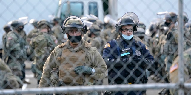 National Guard members and a Washington State Patrol trooper stand behind a perimeter fence, Sunday, Jan. 10, 2021, at the Capitol in Olympia, Wash. Washington Gov. Jay Inslee activated members of the National Guard this week to work with the Washington State Patrol to protect the Capitol campus. A small rally with speakers, flags, and signs representing several groups was held near the fence Sunday, but most attendees had left by early evening. (AP Photo/Ted S. Warren)