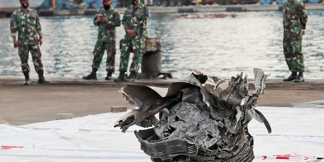 Indonesian marines look at a large part of a plane recovered from the waters off Java Island where Sriwijaya Air flight SJ-182 crashed on Saturday, at Tanjung Priok Port in Jakarta, Indonesia, Monday, Jan. 11, 2021. The search for the black boxes of the crashed Sriwijaya Air jet intensified Monday to boost the investigation into what caused the plane carrying 62 people to nosedive at high velocity into the Java Sea. (AP Photo/Tatan Syuflana)