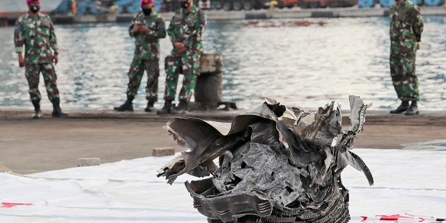 Indonesian marines look at a large part of a plane recovered from the waters off Java Island where Sriwijaya Air flight SJ-182 crashed on Saturday, at Tanjung Priok Port in Jakarta, Indonesia, Monday, Jan. 11, 2021. The search for the black boxes of the crashed Sriwijaya Air jet intensified Monday to boost the investigation into what caused the plane carrying 62 people to nosedive at high velocity into the Java Sea. (AP Photo/Tatan Syuflana)