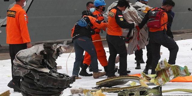 Rescuers carry debris found in the waters around the location where Sriwijaya Air passenger jet crashed at Tanjung Priok Port in Jakarta, Indonesia, Monday, Jan. 11, 2021.  (AP Photo/Achmad Ibrahim)