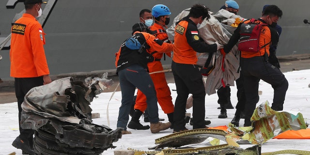 Rescuers carry debris found in the waters around the location where Sriwijaya Air passenger jet crashed at Tanjung Priok Port in Jakarta, Indonesia, Monday, Jan. 11, 2021.  (AP Photo/Achmad Ibrahim)