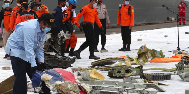 Un investigador del Comité Nacional de Seguridad en el Transporte de Indonesia (KNKT) inspecciona los escombros encontrados en las aguas alrededor del lugar donde se estrelló el avión de pasajeros de Sriwijaya Air en el puerto de Tanjung Priok en Yakarta, Indonesia, el lunes 11 de enero de 2021 (AP Photo / Achmad Ibrahim).