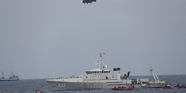 A military helicopter flies past as Indonesian Navy ships continue their search for the wreckage of Sriwijaya Air passenger jet that crashed into Java Sea near Jakarta, Indonesia, Monday, Jan. 11, 2021. Indonesian navy divers scoured the floor of the Java Sea on Monday as they hunted for the black boxes of a Sriwijaya Air jet that nosedived into the waters at high velocity with dozens of people aboard. (AP Photo/Tatan Syuflana)