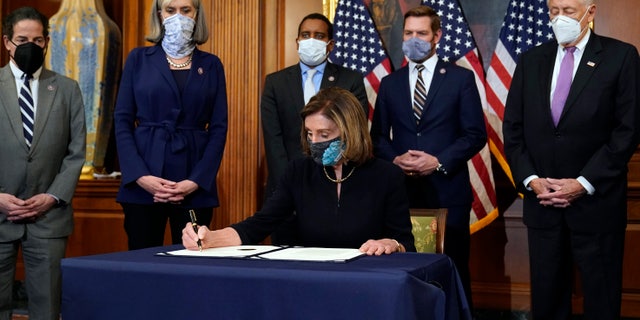 House Speaker Nancy Pelosi of Calif., signs the article of impeachment against President Donald Trump in an engrossment ceremony before transmission to the Senate for trial on Capitol Hill, in Washington, Wednesday, Jan. 13, 2021. (AP Photo/Alex Brandon)