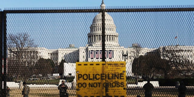 National guards are seen Wednesday, Jan. 13, 2021 on a fence that was erected to reinforce security at the Capitol in Washington. (AP Photo/Shafkat Anowar)