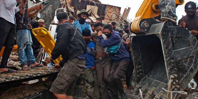 Rescuers assist a survivor pulled out from the ruin of a government building that collapsed during an earthquake in Mamuju, West Sulawesi, Indonesia, Friday, Jan. 15, 2021. (AP Photo/Azhari Surahman)