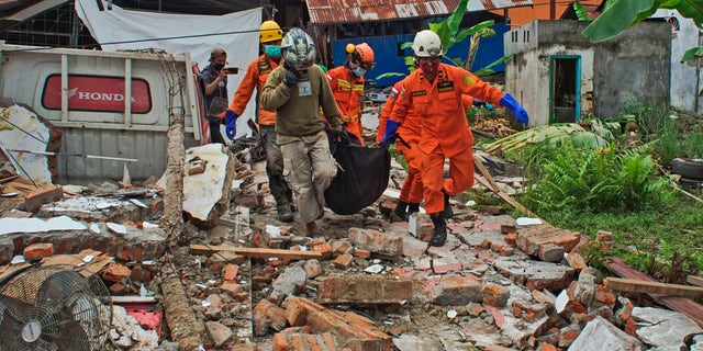 Rescuers carry a body bag containing a victim of an earthquake in Mamuju, West Sulawesi, Indonesia, Friday, Jan. 15, 2021.  (AP Photo/Azhari Surahman)
