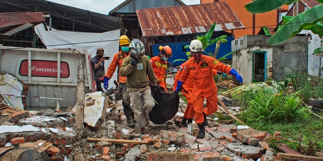 Rescuers carry a body bag containing a victim of an earthquake in Mamuju, West Sulawesi, Indonesia, Friday, Jan. 15, 2021.  (AP Photo/Azhari Surahman)