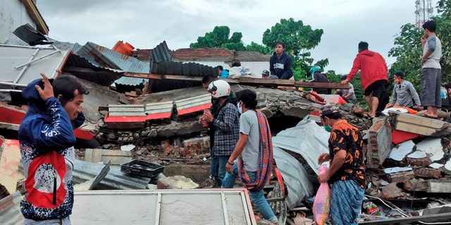 Residents inspect the ruin of a building damaged by an earthquake in Mamuju, West Sulawesi, Indonesia, Saturday, Jan. 16, 2021. (AP Photo/Yusuf Wahil)