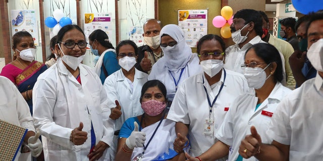 Hospital staff gathers around a health worker, sitting, after she received a COVID-19 vaccine at a government Hospital in Hyderabad, India, Saturday, Jan. 16, 2021. India started inoculating health workers Saturday in what is likely the world's largest COVID-19 vaccination campaign, joining the ranks of wealthier nations where the effort is already well underway. (AP Photo/Mahesh Kumar A.)