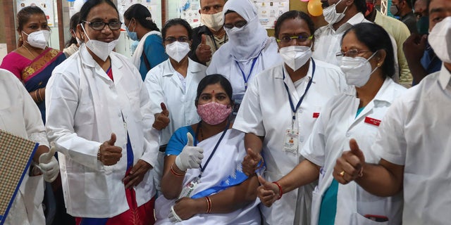 Hospital staff gathers around a health worker, sitting, after she received a COVID-19 vaccine at a government Hospital in Hyderabad, India, Saturday, Jan. 16, 2021. India started inoculating health workers Saturday in what is likely the world's largest COVID-19 vaccination campaign, joining the ranks of wealthier nations where the effort is already well underway. (AP Photo/Mahesh Kumar A.)