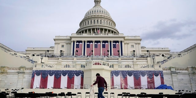 A worker pulls cables as preparations take place for President-elect Joe Biden's inauguration ceremony at the U.S. Capitol in Washington.  Some school districts choose not to live stream the ceremony to classrooms due to concerns about potential violence.  (AP Photo / Patrick Semansky)