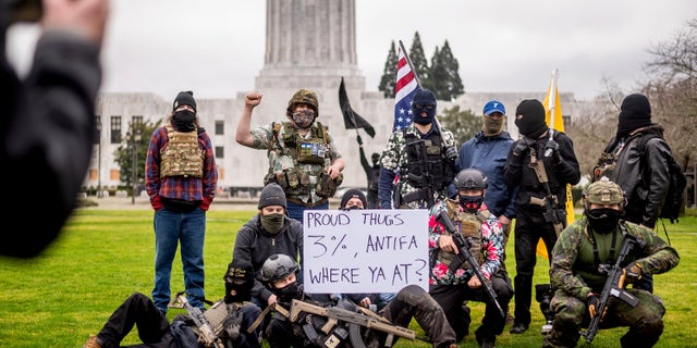 Armed protesters, who identified themselves as Liberty Boys, pose for fellow demonstrators' pictures outside the Oregon State Capitol on Sunday, Jan. 17, 2021, in Salem, Ore. The group said they want reduced government and do not support President Donald Trump or President-elect Joe Biden. (AP Photo/Noah Berger)