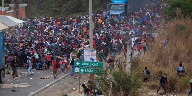 Honduran migrants, top, stand between cargo trucks as they confront Guatemalan soldiers and police blocking them from advancing toward the US, on the highway in Vado Hondo, Guatemala, Monday, Jan. 18, 2021.