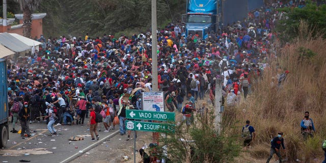 Honduran migrants, above, stand between freight trucks as they clash with Guatemalan soldiers and police who prevent them from advancing towards the United States, on the highway in Vado Hondo, Guatemala, on Monday January 18, 2021.