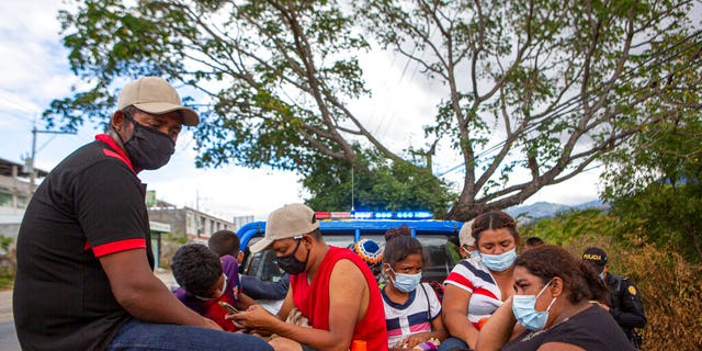 Honduran migrants sit in the bed of a police vehicle after they were detained in Chiquimula, Guatemala, Tuesday, Jan. 19, 2021. (AP Photo/Oliver de Ros)