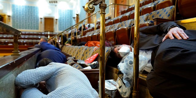 In this Wednesday, Jan. 6, 2021 file photo, people shelter in the House gallery as rioters try to break into the House Chamber at the U.S. Capitol in Washington. (AP Photo/Andrew Harnik, File)