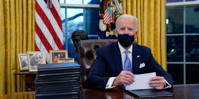 President Biden pauses as he signs his first executive orders at the White House on Jan. 20, 2021.