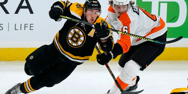 Boston Bruins center Brad Marchand (63) and Philadelphia Flyers defenseman Travis Sanheim (6) skate for position during the third period of an NHL hockey game Thursday, Jan. 21, 2021, in Boston. (AP Photo/Elise Amendola)
