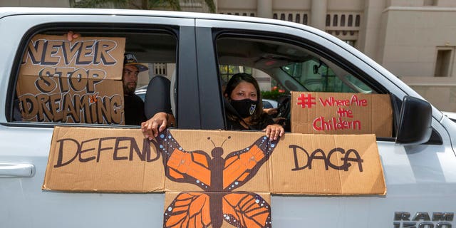 FILE - In this June 18, 2020 file photo, people hold signs during a caravan rally in support of the Deferred Action for Childhood Arrivals Program (DACA) around MacArthur Park in Los Angeles. increase.