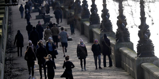 People exercise along the bank of the River Thames in London, Saturday, Jan. 23, 2021, during England's third national lockdown since the coronavirus outbreak began. The U.K. is under an indefinite national lockdown to curb the spread of the new variant, with nonessential shops, gyms and hairdressers closed, and people being told to stay at home. (AP Photo/Kirsty Wigglesworth)