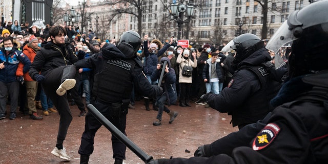 A demonstrator clashes with a police officer during a protest against the jailing of opposition leader Alexei Navalny in Pushkin square in Moscow, Russia, Saturday, Jan. 23, 2021. (AP Photo/Victor Berezkin)