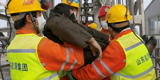 In this photo released by Xinhua News Agency, rescuers carry a miner who was trapped in a gold mine in Qixia City in east China's Shandong Province, Sunday, Jan. 24, 2021. Rescuers in China on Sunday lifted several trapped miners to the surface who were trapped for two weeks after an explosion in a northern gold mine, state media reported. (Luan Qincheng/Xinhua via AP)