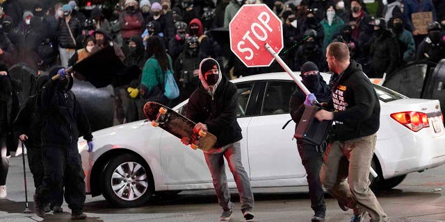 Protesters chase a street preacher, right, who was using a loudspeaker to deliver a sermon during a protest against police brutality, Sunday, Jan. 24, 2021, in downtown Tacoma, Wash., south of Seattle. (AP Photo/Ted S. Warren)
