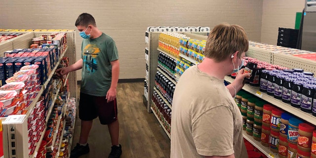 Hunter Weertman, 16, left, stocks shelves and takes inventory while working as a manager of the student-led free grocery store at Linda Tutt High School in Sanger, Texas. (Anthony Love via AP)