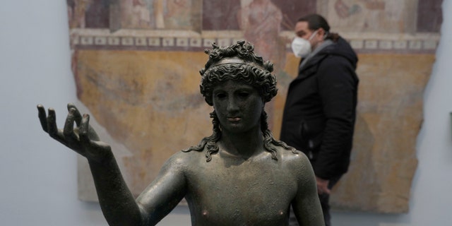 A man walks past the statue of Ephebos inside the museum Antiquarium in Pompeii, southern Italy, Monday, Jan. 25, 2021. The city was destroyed in 79 A.D. by the eruption of Mount Vesuvius.
